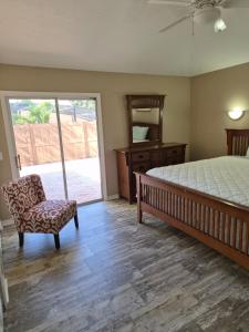 een slaapkamer met een bed en een stoel en een glazen schuifdeur bij The Launch Pad in Titusville