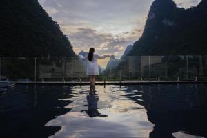 a woman in a white dress standing in a pool of water at Yulonghe Yushan Country Hotel in Yangshuo +159 photos