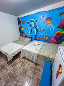 Cette chambre comprend 2 lits et une fresque murale représentant l'océan. dans l'établissement Pousada Rosa de Saron - Algodoal, à Algodoal 11 autres photos
