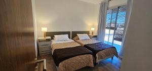 zwei Betten in einem kleinen Zimmer mit Fenster in der Unterkunft Vistas del Yásta cabaña para un solo grupo in Cafayate + 35 Fotos