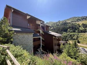 a building on a hill with mountains in the background at Appartement Méribel Mottaret 3 chambres, proche pistes, Wifi - FR-1-355-98 in Méribel