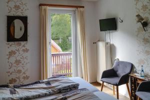 ein Schlafzimmer mit einem Bett, einem Fenster und einem Stuhl in der Unterkunft Gasthaus Talblick - Schwarzwald Plus Karte inkludiert in Baiersbronn
