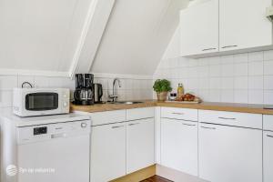 une cuisine avec des armoires blanches et un micro-ondes dans l'établissement Mooie rustige woning Overijssel, à Gramsbergen
