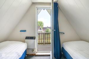 ein Schlafzimmer mit zwei Betten und einem Balkon in der Unterkunft Mooie rustige woning Overijssel in Gramsbergen + 21 Fotos