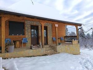 Una cabaña de madera con un porche en la nieve. en Tarin zov, en Kaludjerske Bare