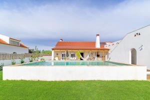 a villa with a swimming pool and a house at Casa do Medronheiro in Melides
