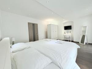 ein weißes Schlafzimmer mit einem großen weißen Bett und einem Schreibtisch in der Unterkunft Old City Poema in Braşov