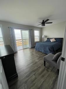 a bedroom with a bed and a couch and a fan at Oceanfront Cottage w/ Upper Balcony View in Summerside