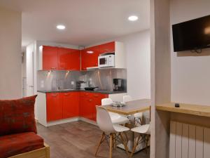 eine Küche mit roten Schränken und einem Tisch mit weißen Stühlen in der Unterkunft Appartement rénové confortable, animaux admis, centre station - FR-1-181-906 in Plagne Bellecôte