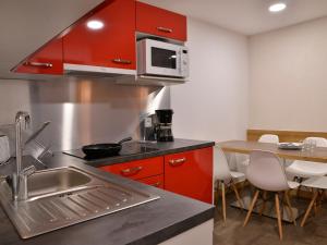 eine Küche mit roten Schränken, einer Spüle und einem Tisch in der Unterkunft Appartement rénové confortable, animaux admis, centre station - FR-1-181-906 in Plagne Bellecôte