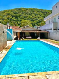 ein großer blauer Swimmingpool vor einem Haus in der Unterkunft Casa na praia do Guaiuba in Guarujá