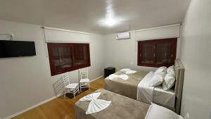 een kamer met 2 bedden en een flatscreen-tv bij Cores De Outono Suítes in Canela