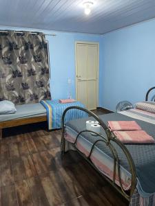two beds in a room with blue walls and wooden floors at Suíte rural in Foz do Iguaçu