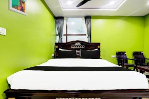 a bedroom with a bed with green walls and chairs at Hotel O Savoy Grand in Warangal