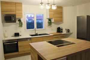 eine Küche mit Holzschränken und einem Edelstahlkühlschrank in der Unterkunft Maison cosy - Logis Flo - à 15 min du Futuroscope in Beaumont