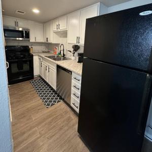 Una cocina con refrigerador negro y gabinetes blancos. en 1 DT Dallas l FIFA WORLD CUP READY l 5 Min from Love Field, en Dallas 16 fotos más