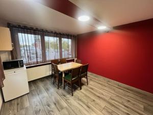 a kitchen with a table and chairs and a red wall at Pension Baron in Fürth