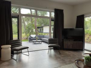 un soggiorno con divano, sedie e TV di Ommerland a Ommen