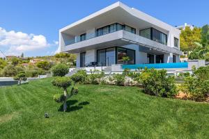 a large white house with a green yard at Aurora Residence by A&D Properties in Neos Voutzas