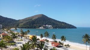 a view of a beach with palm trees and the ocean at Suite Recanto Cheiro Verde in Caraguatatuba