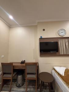Zimmer mit einem Schreibtisch, einem Bett und einer Uhr in der Unterkunft فندق قصر ماريوت 1 in Al ‘Azīzīyah