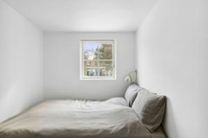ein Bett in einem weißen Zimmer mit einem Fenster in der Unterkunft Smukt Familiesommerhus I Vejby in Vejby Strand