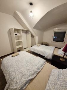 a bedroom with two beds and a flat screen tv at Le Coty duplex - 5min chantier et 250m plage in Saint-Nazaire