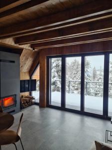 Una sala de estar con chimenea y grandes ventanales. en Gorje Tara, en Sekulić 