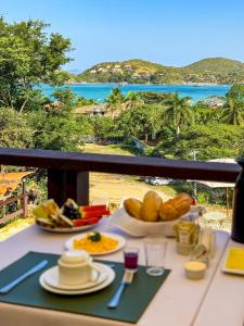 a table with food and a view of the ocean at Pousada Encanto de Búzios in Búzios +57 photos