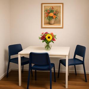 a table with chairs and a vase of flowers on it at Ferienwohnung Las Vegas in Marienheide