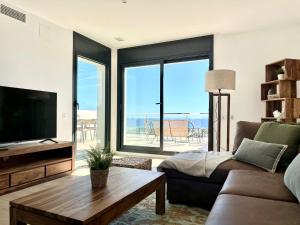 a living room with a couch and a tv and a table at Les Flors de Cunit Villa Cedra in Cunit