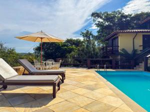 a patio with an umbrella and a swimming pool at Pousada Encanto de Búzios in Búzios