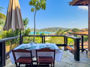 a table and chairs on a balcony with a view of the ocean at Pousada Encanto de Búzios in Búzios