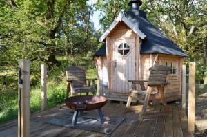 una terraza de madera con una casita de juegos y dos sillas en Pine Marten, en Kilmichael Glassary