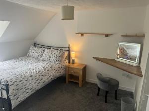 a bedroom with a bed and a table and a chair at Highland Park Cottage in Kirkwall