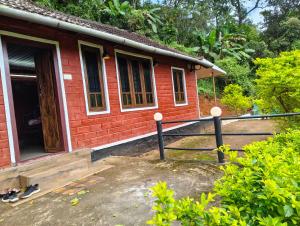 a small red brick house with a porch at Clay Canvas in Anachal