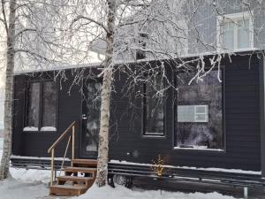 a black house in the snow with a tree at Santa Elves Cabin in Rovaniemi +29 photos