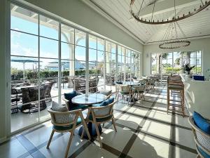 un restaurant avec des tables et des chaises et de grandes fenêtres dans l'établissement Nova Word Phan Thiết - The Moon The Moon Villa, à Bình Tú