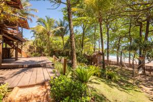 a wooden walkway leading to the beach with palm trees at Pousada Canto Bravo in Ilhabela