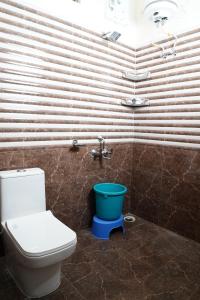 La salle de bains est pourvue de toilettes et d'un seau bleu. dans l'établissement Sukoon Inn Hotel & Restaurant, à Someshwar
