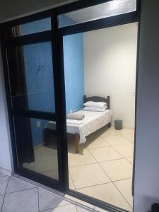 Schlafzimmer mit einem Bett und einem Glasfenster in der Unterkunft Conexão conforto in Vespasiano