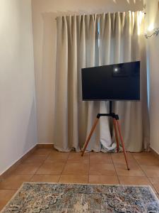 Ein Flachbildfernseher auf einem Stativ vor einem Vorhang in der Unterkunft Ferienwohnung Heidi in Prien am Chiemsee