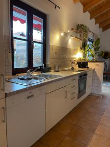 eine Küche mit weißen Schränken und einer Spüle und Fenstern in der Unterkunft Ferienwohnung Heidi in Prien am Chiemsee