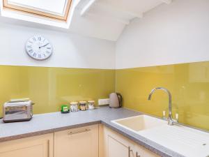 a kitchen with a sink and a clock on the wall at Bay - Uk44720 in Ravenscar +2 photos
