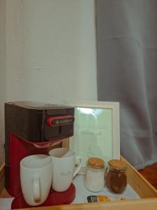 une cafetière et deux tasses sur une table dans l'établissement Wind Village Icaraizinho, à Icaraí