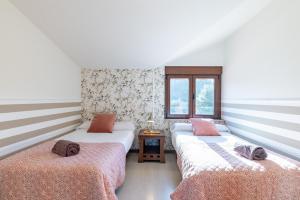 - 2 lits dans une chambre aux murs rayés dans l'établissement Villa Carolina Luxury Singular, à Basoñas