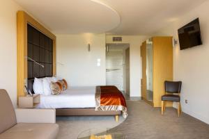 a hotel room with a bed and a chair at LE VAL MORET Hôtel Restaurant et Spa in Magnant
