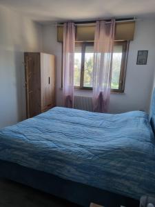 ein Schlafzimmer mit einem blauen Bett und zwei Fenstern in der Unterkunft Affittacamere Ely in San Giórgio di Nogaro
