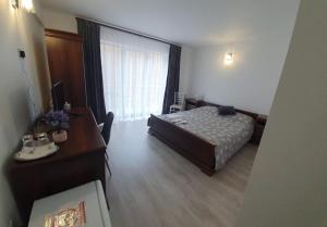 a bedroom with a bed and a desk and a window at Casa Bogdan in Uricani