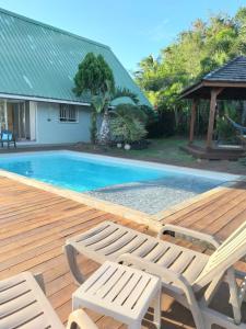 una terraza de madera con 2 sillas y una piscina en Manuia Lodge, en Punaauia